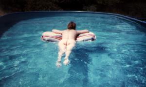 Зрелая женщина плавает в бассейне и загорает обнаженная - фото #11
